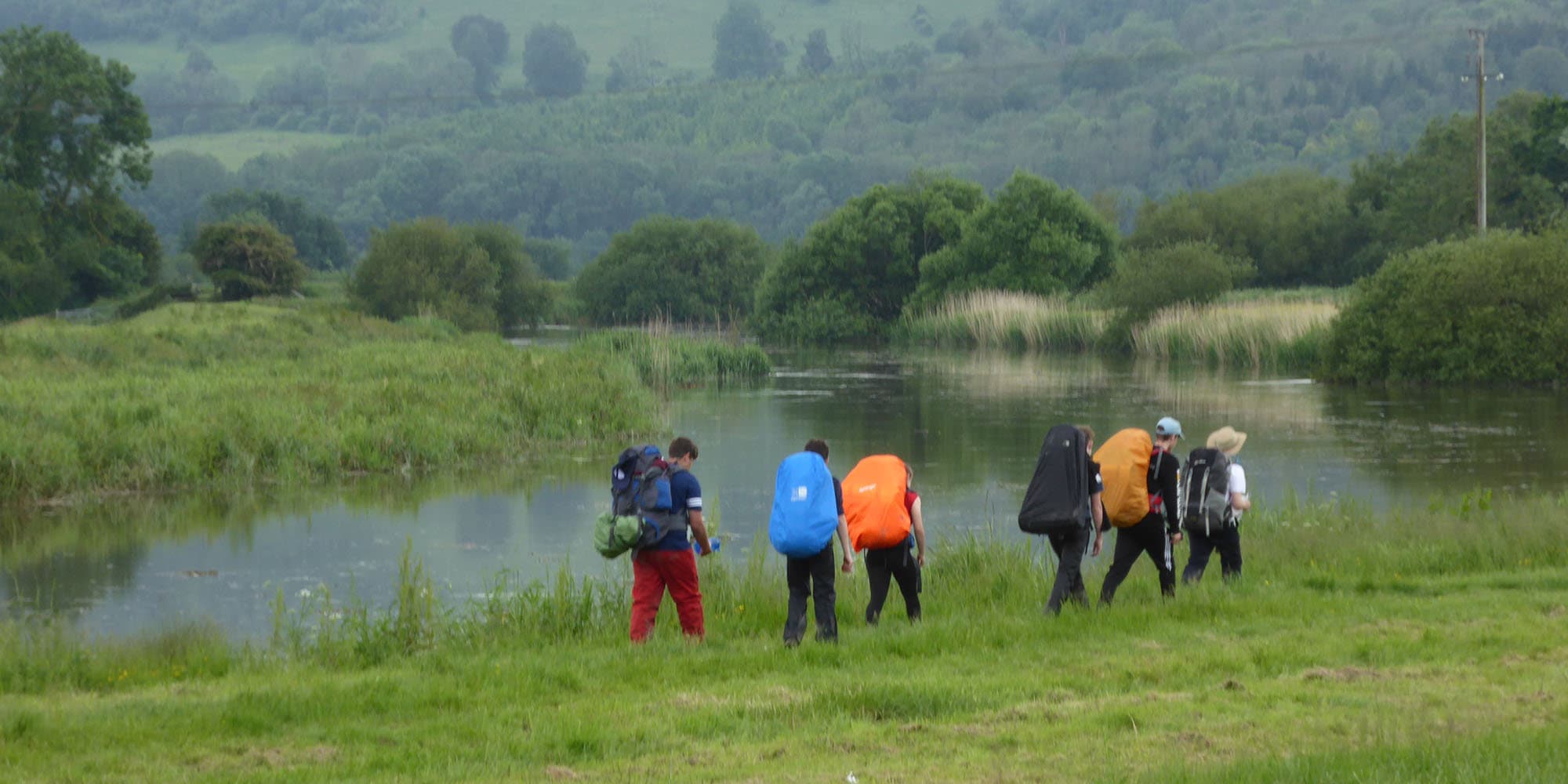 Walkers with rucksacks beside a river